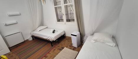 Une chambre à coucher avec un lit, un radiateur, une fenêtre et un chauffage d’appoint.