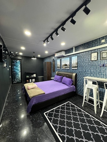 A modern bedroom with a bed, a desk, and a patterned rug.