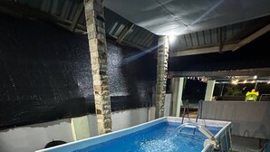 An indoor swimming pool with a clear blue water surface, surrounded by artificial grass and concrete walls.
