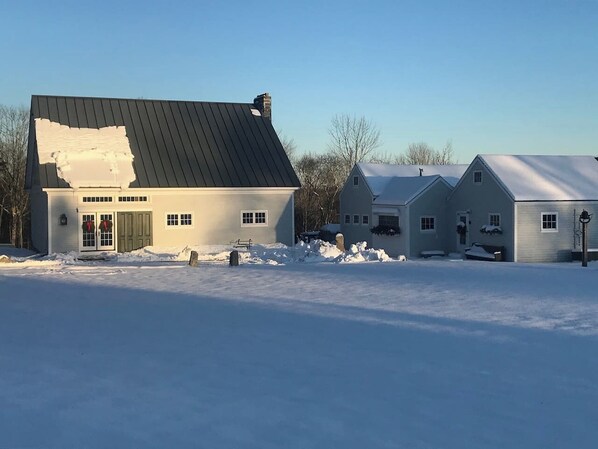 A residential area with a house featuring a dark roof and a front door with a green door frame. - Thistledown Farm's Pennysworth - An 1800's barn. (Waldoboro)