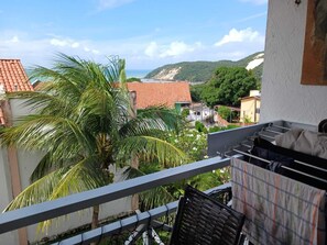 A balcony with a view of a coastal town, a palm tree, and a mountain in the background. - Petit nid d'amour in Ponta Negra (Natal)