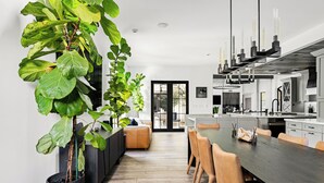 Una cocina moderna con comedor, plantas grandes en macetas y un diseño minimalista.