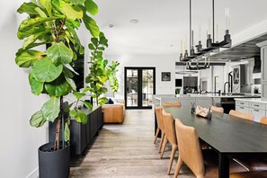 A modern kitchen with a dining area, large potted plants, and a minimalist design. - New North Scottsdale RH Residence (Scottsdale)