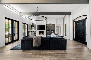 A modern living room with a sectional sofa, a fireplace, and a large chandelier. - New North Scottsdale RH Residence (Scottsdale)