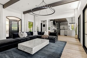 A modern living room with a sectional sofa, a marble coffee table, and a large circular chandelier. - New North Scottsdale RH Residence (Scottsdale)