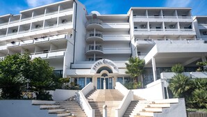 Ein mehrgeschossiges Hotel mit einer zentralen Treppe, Balkonen und blauem Himmel.