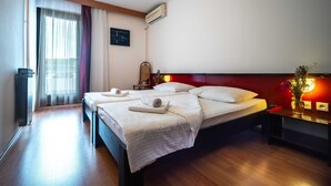Ein Hotelzimmer mit einem großen Bett, einem Nachttisch mit Lampe, einem Heizkörper und einem Fenster mit Vorhängen.