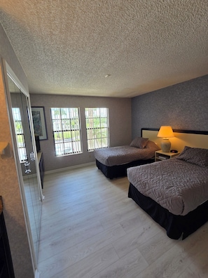 Een slaapkamer met twee bedden, een nachtkastje, een lamp en een raam met tralies.