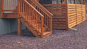 Eine zweistöckige Holzterrasse mit einer Treppe, die zu einer überdachten Veranda führt.