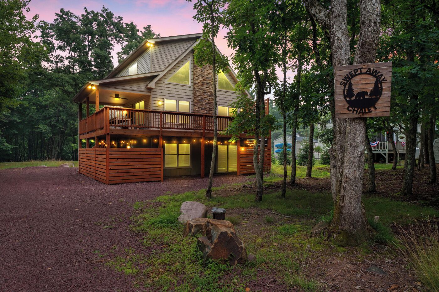 A cabin with a deck, large windows, and a sign reading 'Swept Away Chalet'.