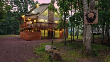 A cabin with a deck, large windows, and a sign reading 'Swept Away Chalet'.