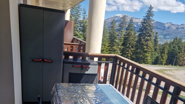 Ein Balkon mit Glastisch, Stühlen und Holzgeländer.