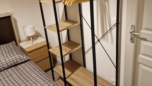Ein Schlafzimmer mit Bett, Nachttisch, Kommode und Kleiderschrank mit Regalen.
