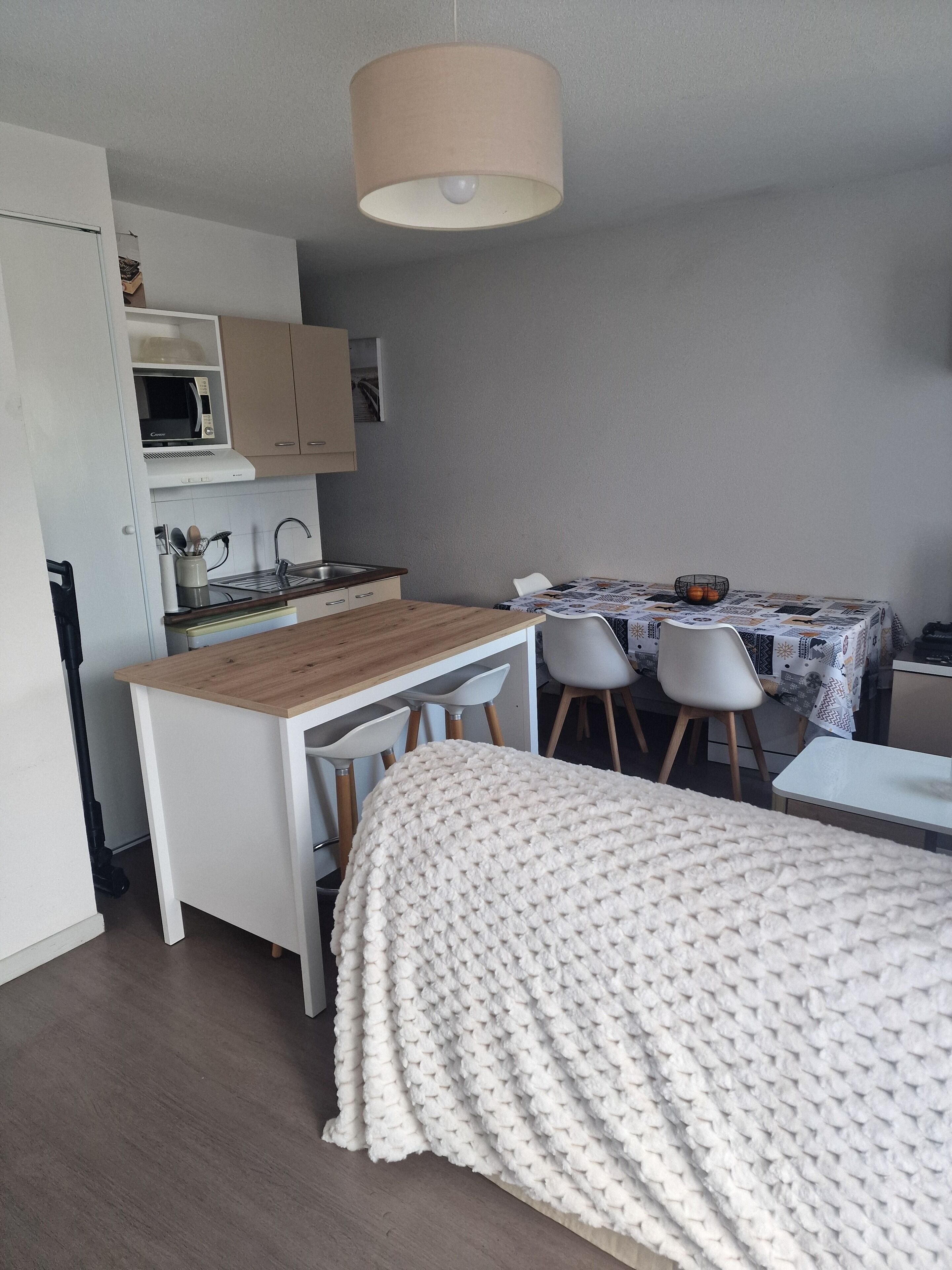 A compact kitchen with a microwave, sink, and a dining area with a table and chairs.