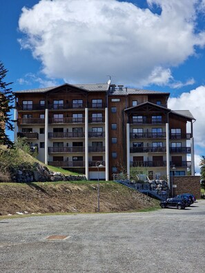 A multi-story wooden building with balconies, a gravel driveway, and a clear sky. - Stunning 2-room apartment for 6 people at the foot of the Chabanon slopes (Selonnet)