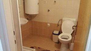 Un baño pequeño con inodoro, lavamanos y un cubo de basura.