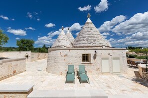 A stone building with conical roofs, a small window, and two green lounge chairs. - Trulli La Quercia del Nonno by BarbarHouse (Locorotondo)