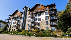 A multi-story hotel with balconies, stone facade, and a paved entrance.