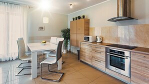 A modern kitchen with a dining area, stainless steel appliances, and a built-in oven.