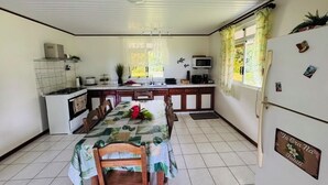 Cocina compacta con una mesa de comedor para cuatro personas, un refrigerador y un microondas.