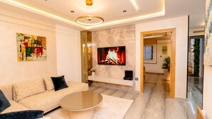 Un salon moderne comprenant un canapé, une table basse, un téléviseur, une cheminée et un couloir menant à une autre pièce.