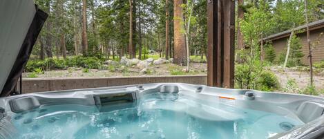 Un jacuzzi con cubierta de madera y vista al bosque.