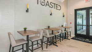L’intérieur d’un café au design moderne, avec des tables et des chaises disposées pour accueillir les clients.