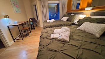 Una camera d'albergo con due letti, una scrivania, una sedia e un grande specchio.