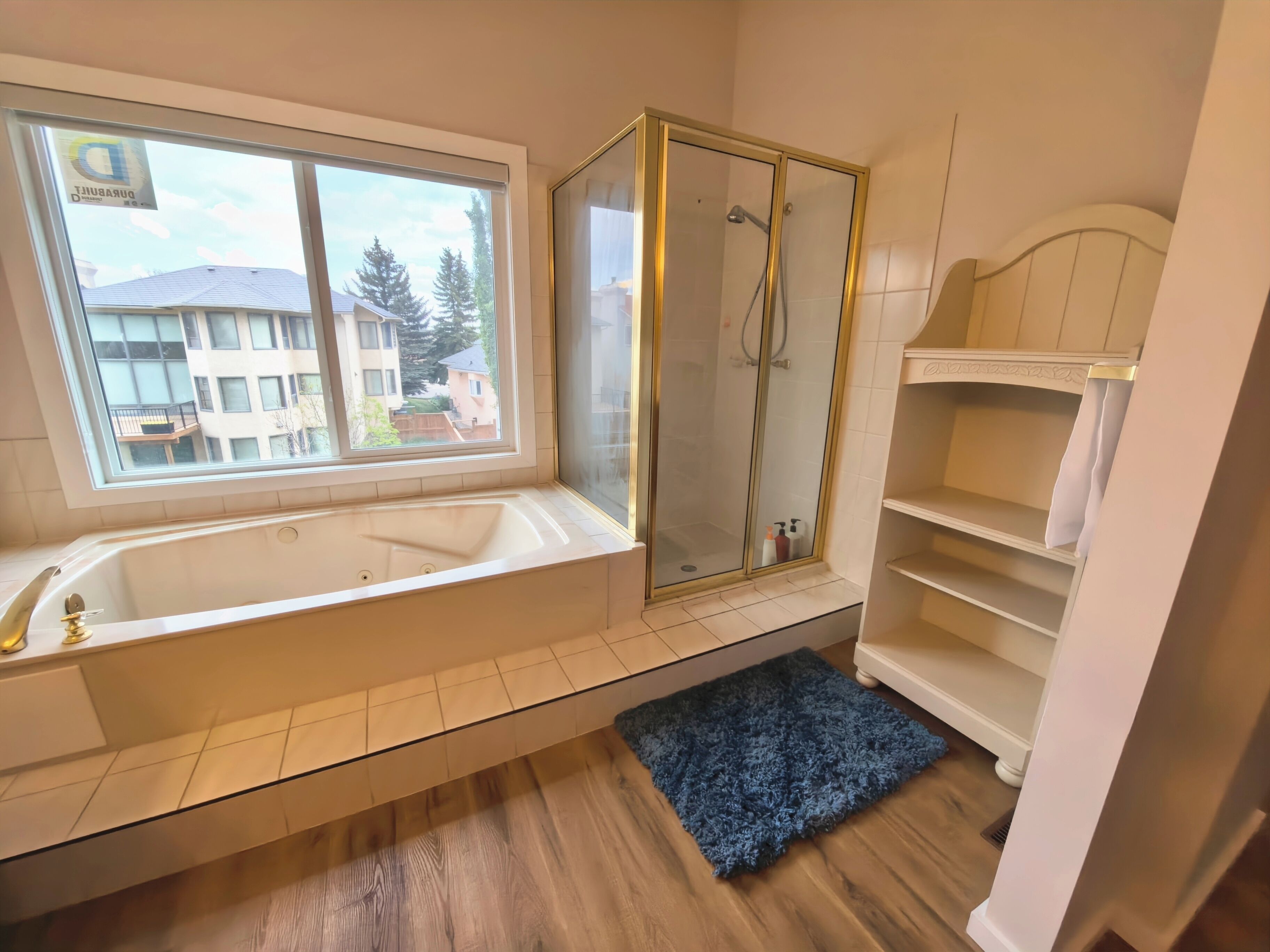 Ein Badezimmer mit Badewanne, Duschkabine, Fenster und Blick auf Gebäude.