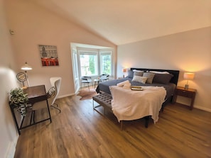 A modern bedroom with a large bed, bedside tables, a desk, and a chair. - Metta Stays Edgemont (Calgary)