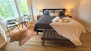 A bedroom with a large bed, two bedside lamps, a chair, a small table, and a rug.