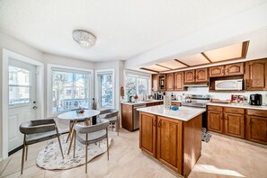 A modern kitchen with wooden cabinets, a central island, and a dining area with chairs.