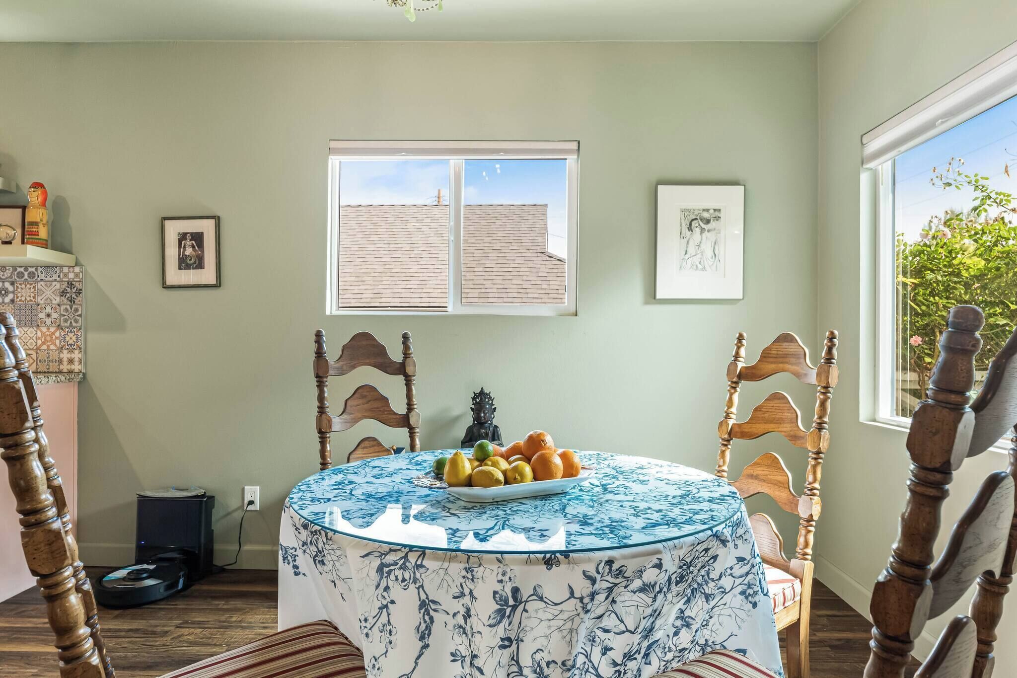Un comedor con una mesa redonda cubierta por un mantel azul con motivos florales, rodeado de sillas de madera.