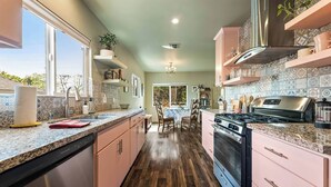 A kitchen with granite countertops, stainless steel appliances, and pink cabinetry.