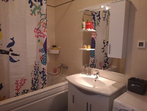 Ein Badezimmer mit Badewanne, Waschbecken, Spiegel und Ablagen für Toilettenartikel.