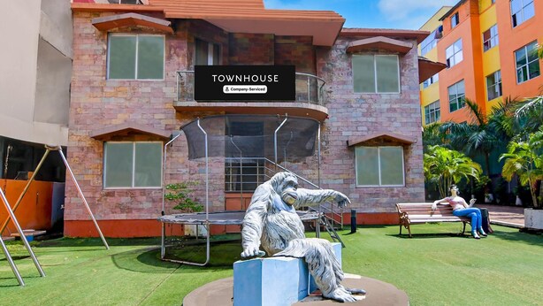 A building labeled 'TOWNHOUSE' with a balcony, a statue of a gorilla, and a person sitting on a bench.
