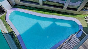 A swimming pool with a tiled deck and a metal railing.