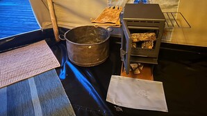 A portable stove with a pot and a firewood rack inside a tent. - 4 Person Holiday Home in Sejero (Sejero)