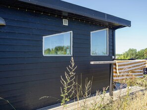 A dark wooden building with two windows and a small vent. - 4 Person Holiday Home in Sejero (Sejero)