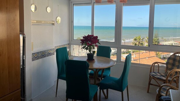 Ein Essbereich mit Meerblick, ein runder Tisch, blaue Stühle und ein Blumentopf.