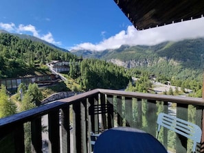 A balcony with a view of a mountainous landscape, a wooden deck, and a chair. - 100m from ski slopes, 6th floor, view mountain, balcony, tv, 25m², Les Orres (Les Orres)