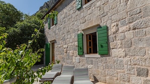 A stone building with a courtyard, green shutters, and lounge chairs. - Amazing Villa in Omis With Private Pool (Omis)