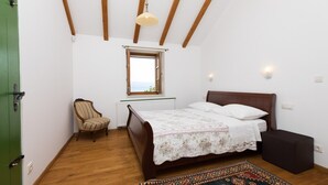 A bedroom with a wooden bed, a chair, a window, and a radiator. - Amazing Villa in Omis With Private Pool (Omis)