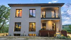 Een modern gebouw met twee verdiepingen, grote ramen, een balkon en een goed verlichte ingang.