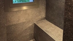 Een badkamer met raam, douchegedeelte en uitzicht op groen.