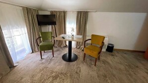 Una habitación con una mesa de comedor, dos sillas, un televisor y un radiador.