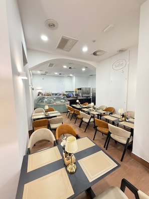 Un interior de restaurante con mesas, sillas y una zona de bar.