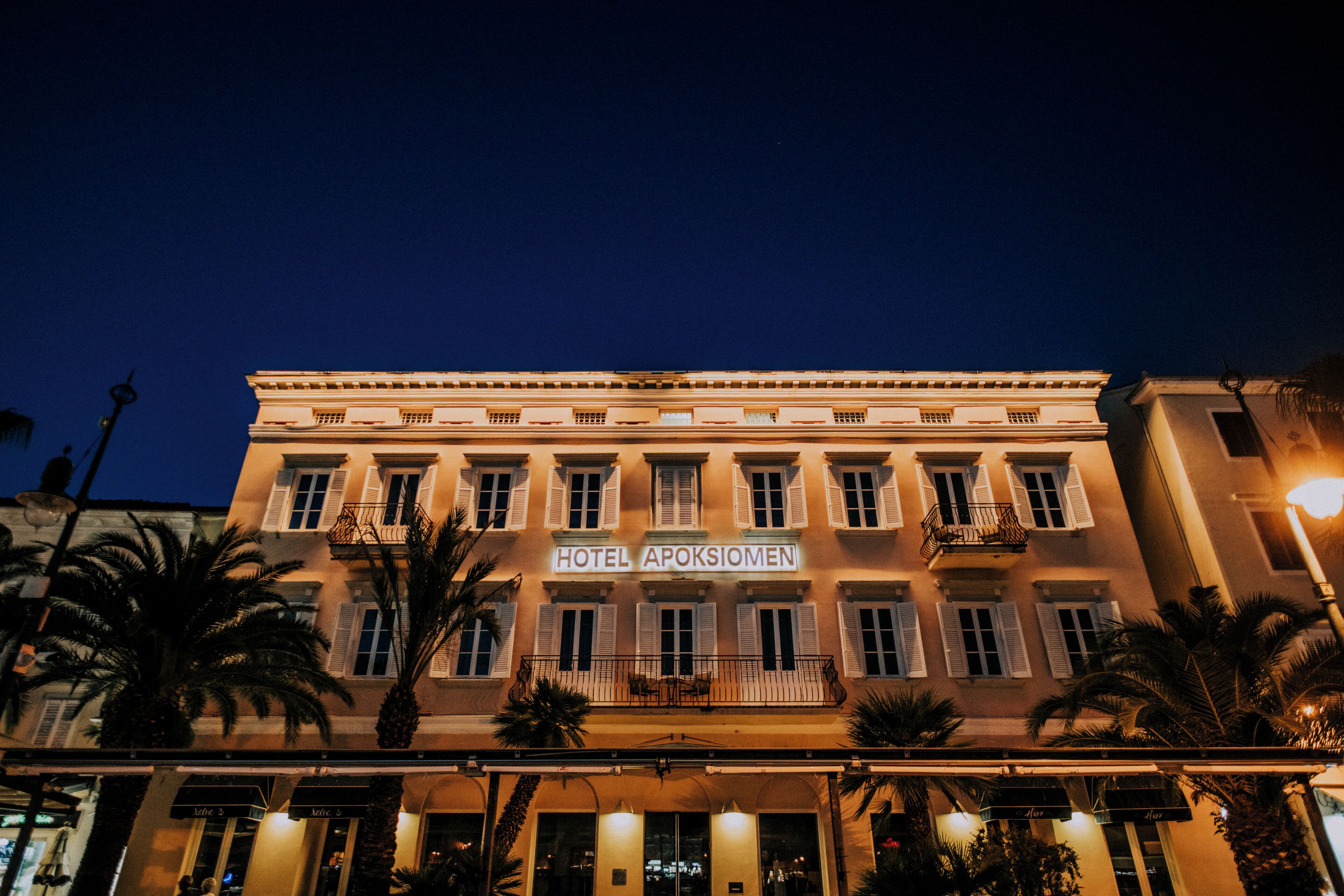 A hotel building with a sign reading 'HOTEL APOSTIOMEN' at night.