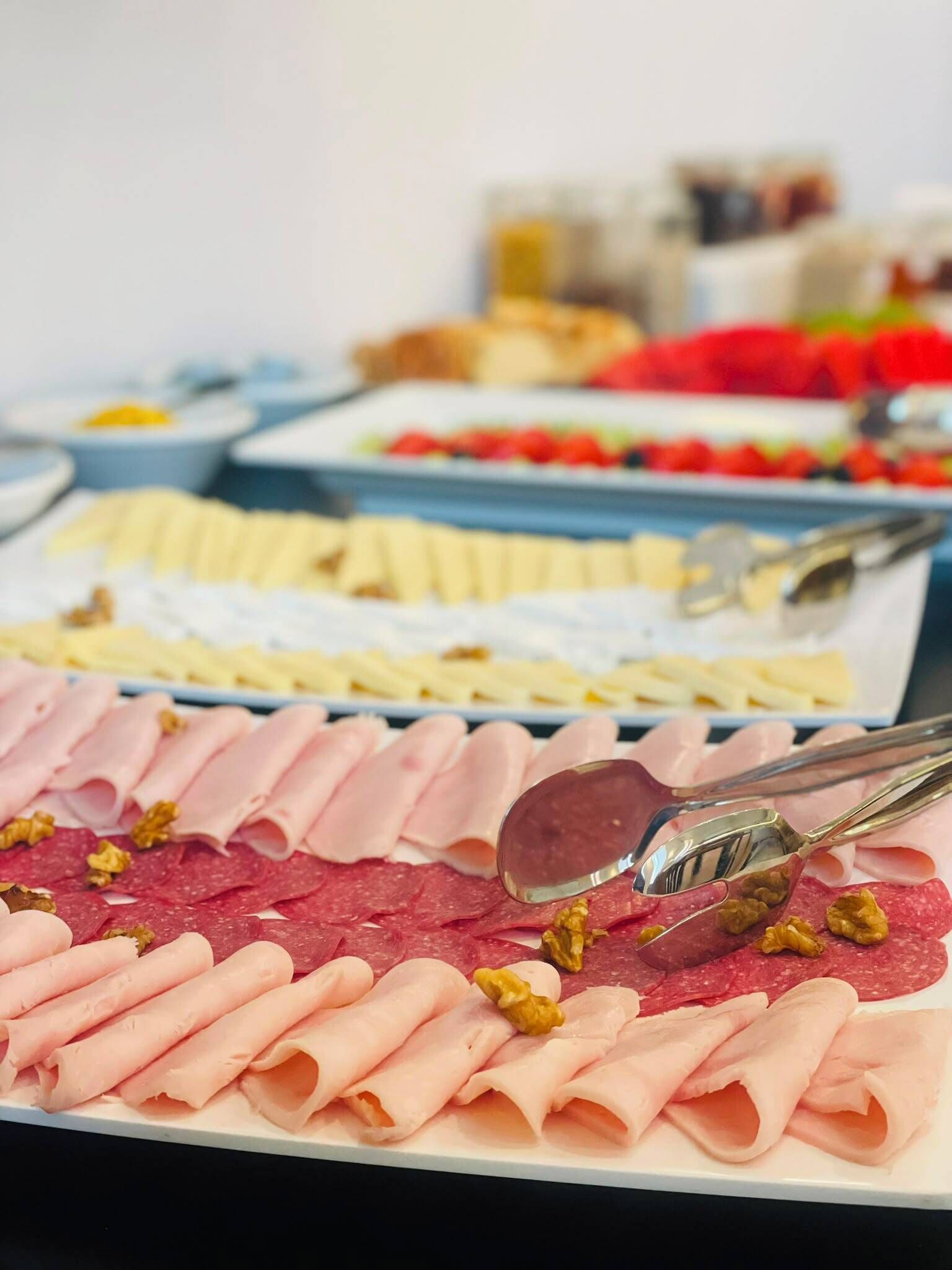 A variety of food items including sliced meats and fruits on a buffet table.