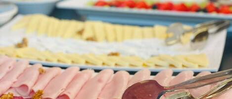 A variety of food items including sliced meats and fruits on a buffet table.